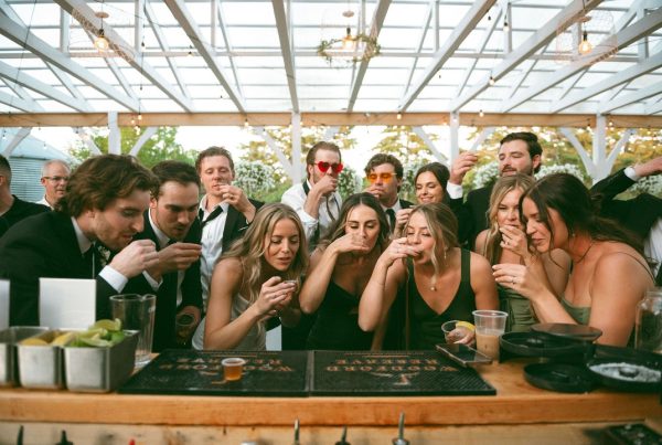 Group of friends enjoying celebratory drinks at a lively party under a decorated outdoor pavilion.